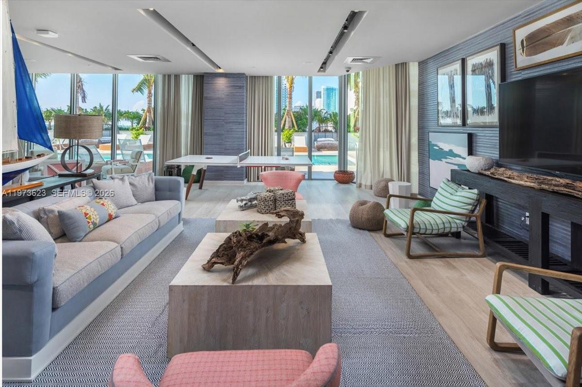 A modern living room features a ping pong table, blue textured walls, and floor-to-ceiling windows — 2900 NE 7th Ave # 3004, Miami FL 33137, MIAMI, FL