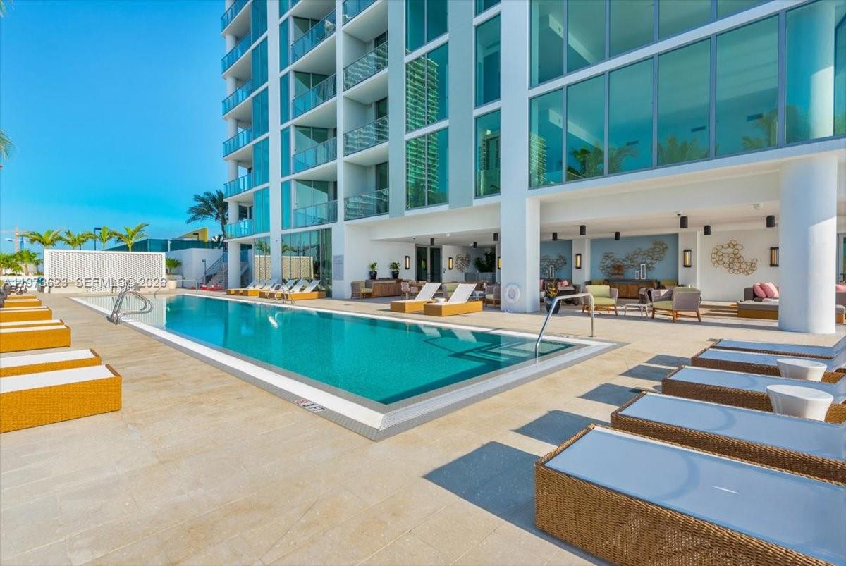 A modern outdoor swimming pool area features lounge chairs on a paved deck by a building — 2900 NE 7th Ave # 3004, Miami FL 33137, MIAMI, FL