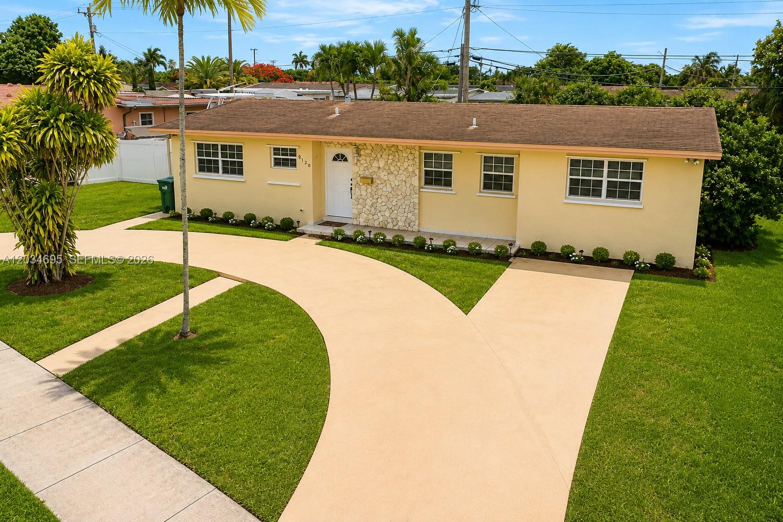 A single-story yellow house features a stone facade, a curved driveway, and a grassy lawn — 9120 SW 16th St, Miami FL 33165, MIAMI, FL