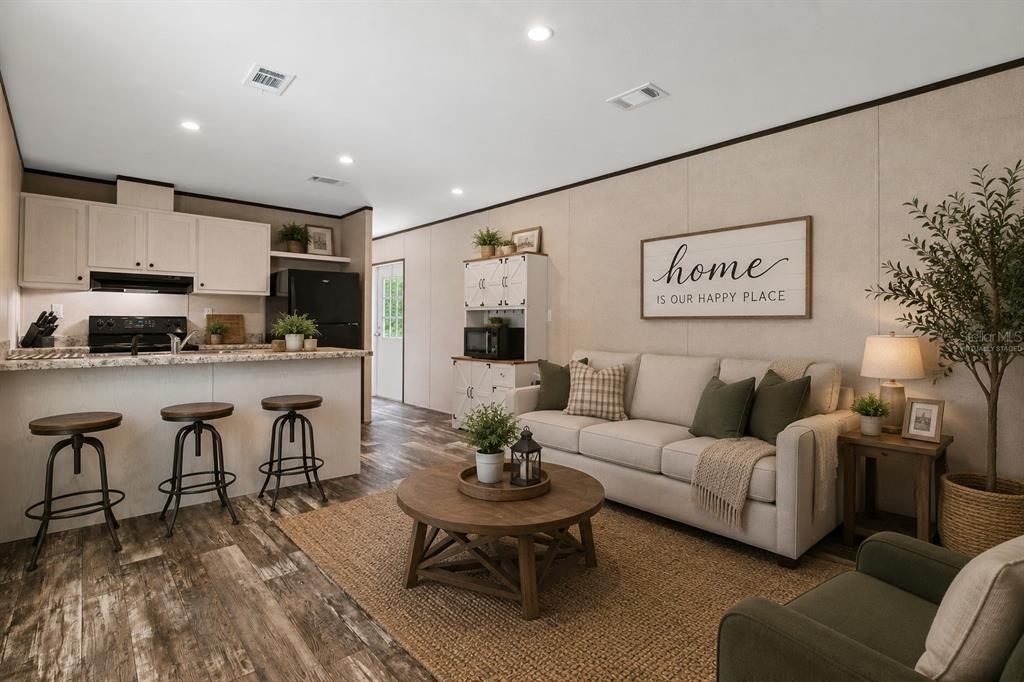 A living room and kitchen area with light wood walls, a sofa, and bar stools — 4363 CR 690, WEBSTER, FL
