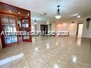 A spacious room with light-colored tile flooring, recessed lighting, and a wooden-framed glass door — 2351 SW 92nd Pl, Miami FL 33165, MIAMI, FL