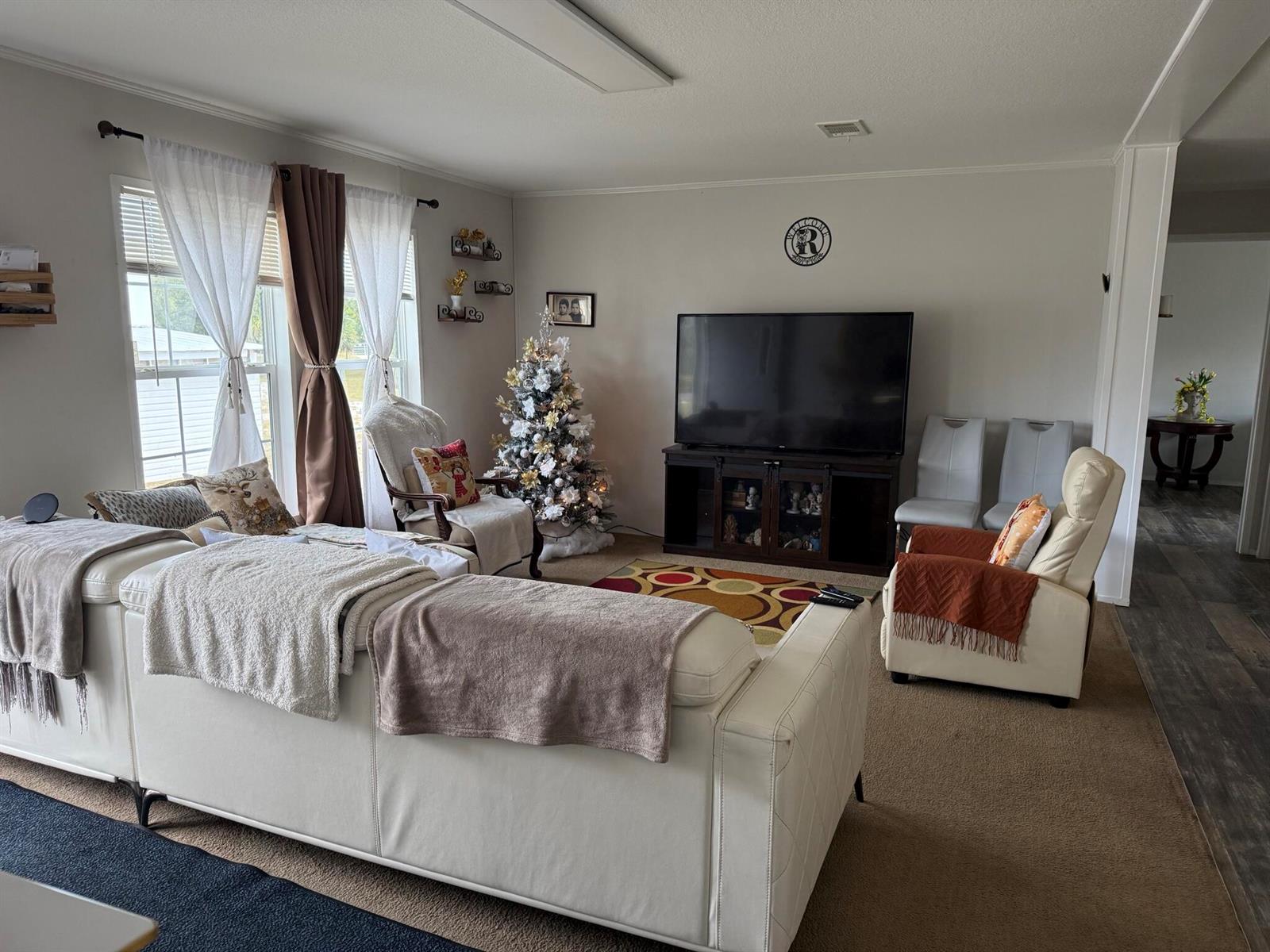 A living room features a white sectional sofa, a television on a stand, and a Christmas tree — 15628 NW 310th Street, Okeechobee FL 34972, OKEECHOBEE, FL