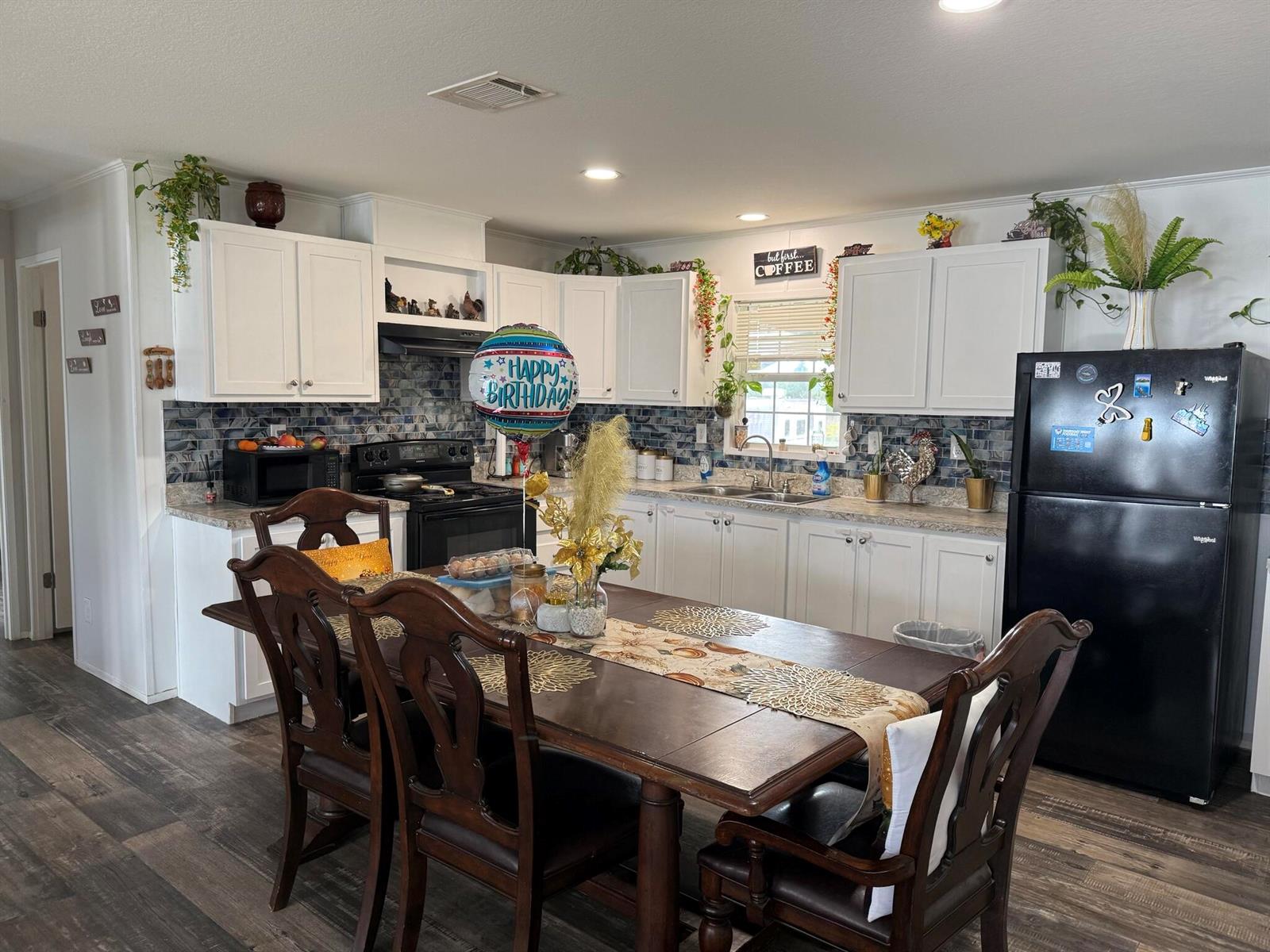 A kitchen with white cabinets, a dark wood dining table, and a black refrigerator — 15628 NW 310th Street, Okeechobee FL 34972, OKEECHOBEE, FL