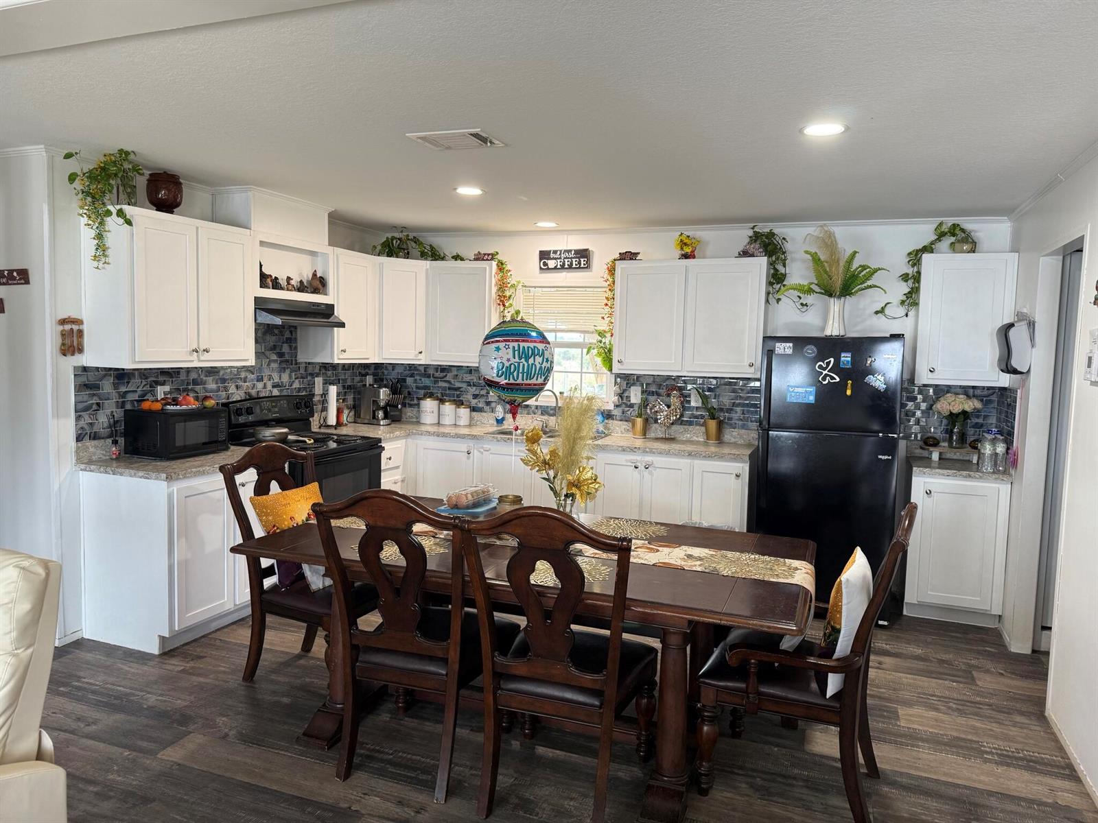 A kitchen with white cabinets, dark wood dining furniture, and a black refrigerator — 15628 NW 310th Street, Okeechobee FL 34972, OKEECHOBEE, FL