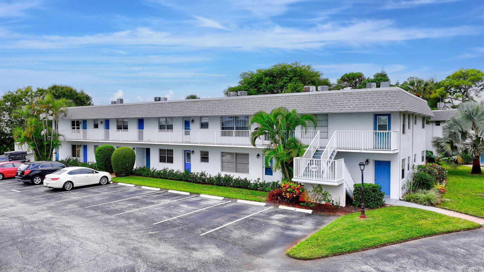 A two-story apartment building with a parking lot, white railings, and blue doors — 2929 SE Ocean Boulevard # 7, Stuart FL 34996, STUART, FL