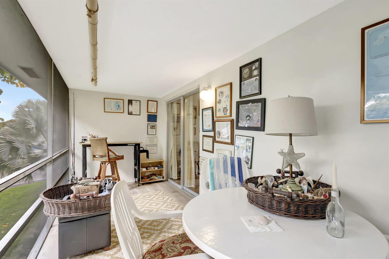 A sunroom features a white round table, a desk, and framed wall art — 2929 SE Ocean Boulevard # 7, Stuart FL 34996, STUART, FL