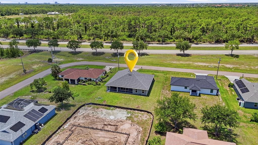 An aerial view shows a residential neighborhood with several houses, a construction site, and trees — 1927 NE 33RD STREET, CAPE CORAL, FL