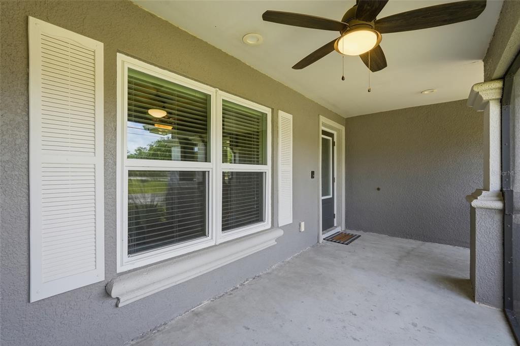 A covered porch features a ceiling fan, a window with shutters, and a glass door — 1927 NE 33RD STREET, CAPE CORAL, FL
