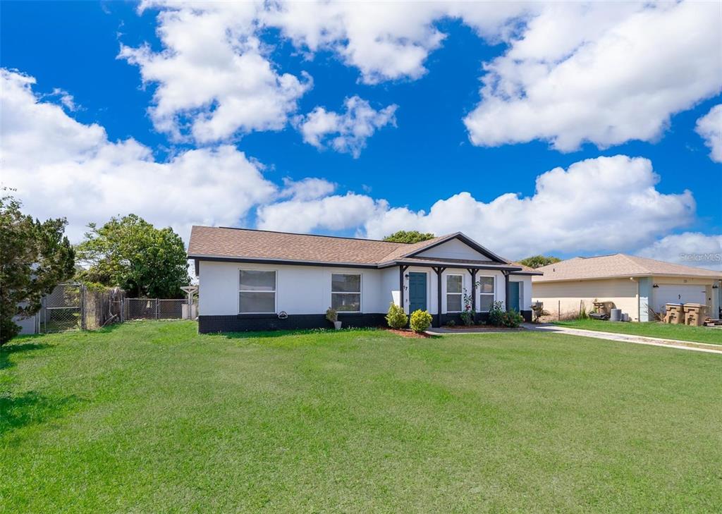 A single-story house with a white exterior, dark trim, and a large front lawn — 17 TROTTERS CIRCLE, KISSIMMEE, FL