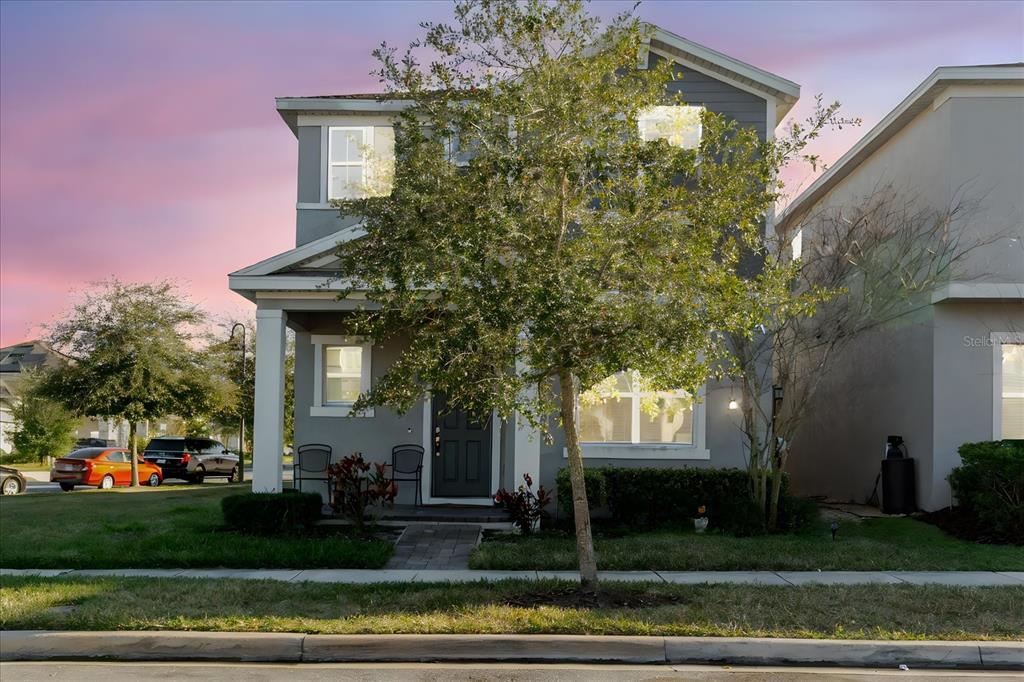 A two-story gray house with a front porch and a tree in the yard — 16012 MICELLI DRIVE, WINTER GARDEN, FL