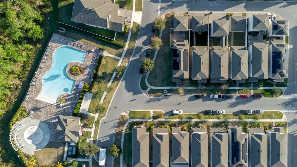 This aerial view shows a community pool, clubhouse, and several rows of townhomes — 16012 MICELLI DRIVE, WINTER GARDEN, FL