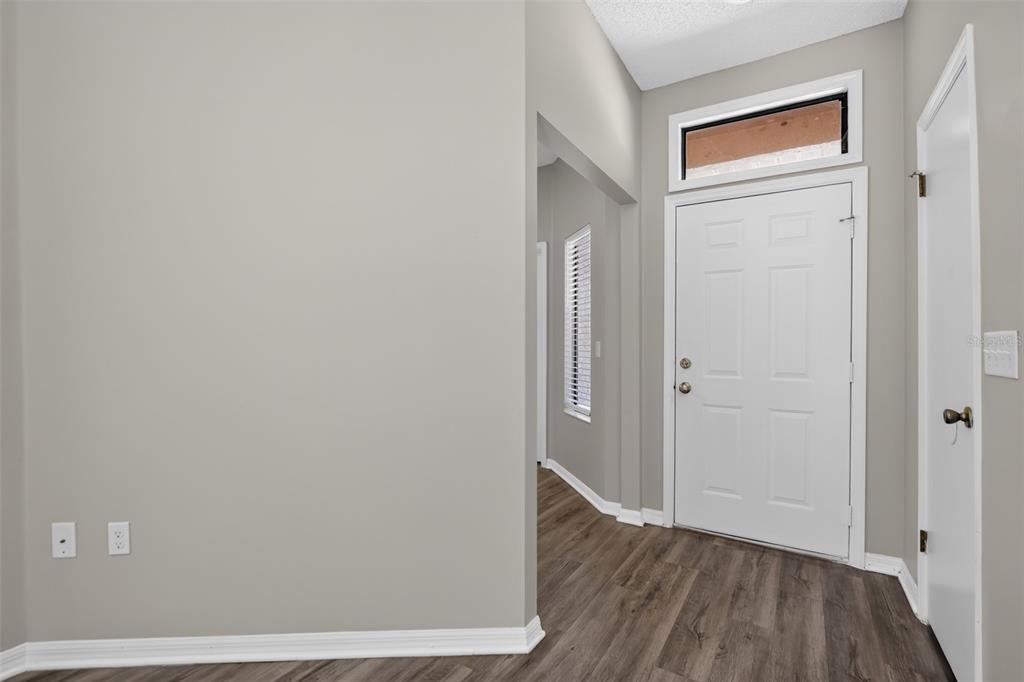 An entryway with gray walls, wood-look flooring, a white front door, and a side closet — 6348 SLEEPY HOLLOW DRIVE, ORLANDO, FL