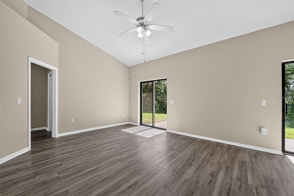 An empty room with wood-look flooring, a vaulted ceiling, a ceiling fan, and sliding doors — 6348 SLEEPY HOLLOW DRIVE, ORLANDO, FL