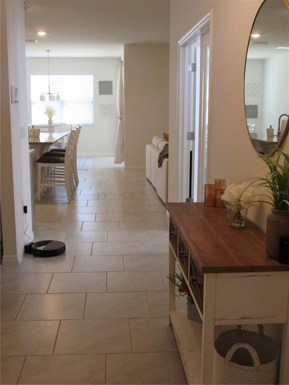 A hallway with tile flooring leads from a console table toward a kitchen and living area — 1739 RED ROCK ROAD, NEW SMYRNA BEACH, FL