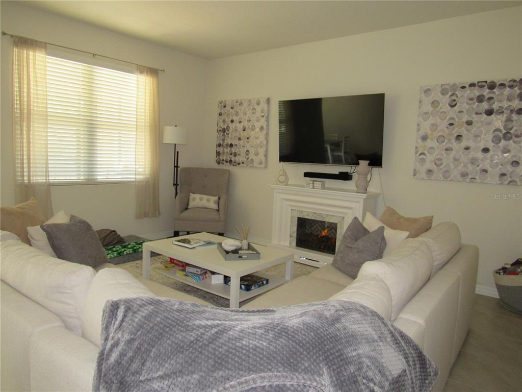 A living room features a white sectional sofa, a coffee table, and a wall-mounted television — 1739 RED ROCK ROAD, NEW SMYRNA BEACH, FL