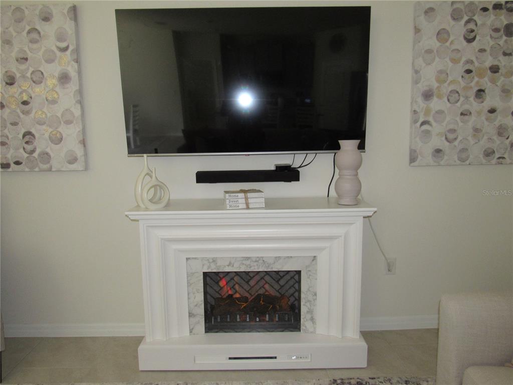 A wall-mounted television sits above a white fireplace mantel with a decorative electric insert — 1739 RED ROCK ROAD, NEW SMYRNA BEACH, FL