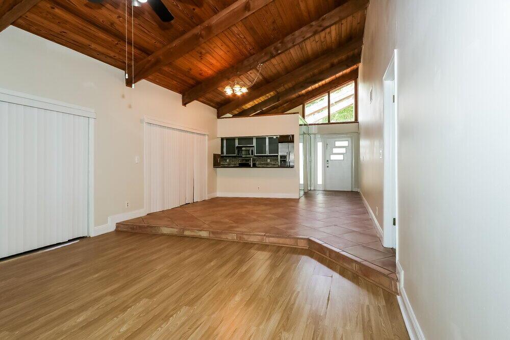 A living room with a vaulted wood ceiling, tile-floored dining area, and light wood flooring — BOCA RATON, FL