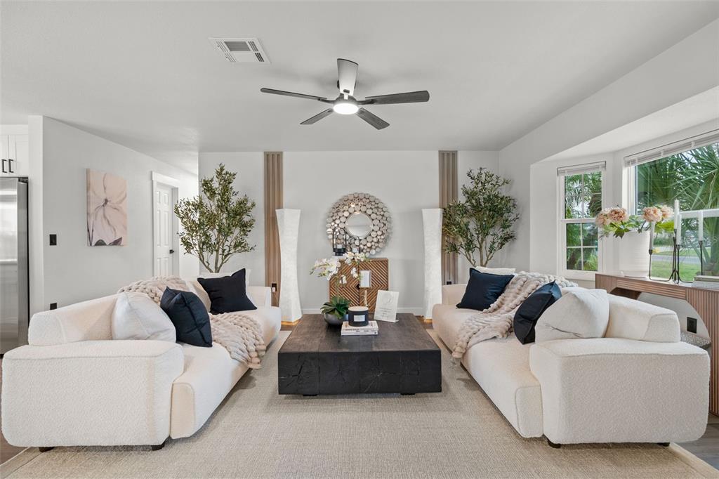 A living room features two white sofas, a dark coffee table, and symmetrical floor lamps — 30 OAKLAND HILLS COURT, ROTONDA WEST, FL