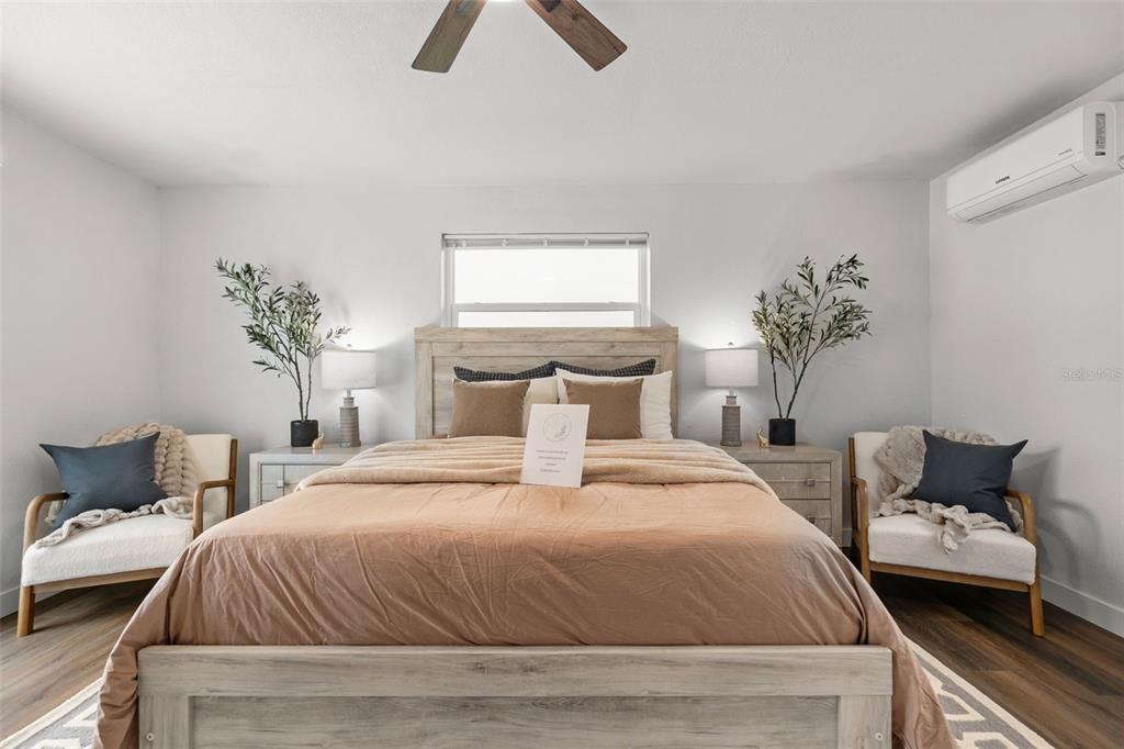 A bedroom features a central bed, two side chairs, nightstands with lamps, and a wall-mounted AC — 30 OAKLAND HILLS COURT, ROTONDA WEST, FL
