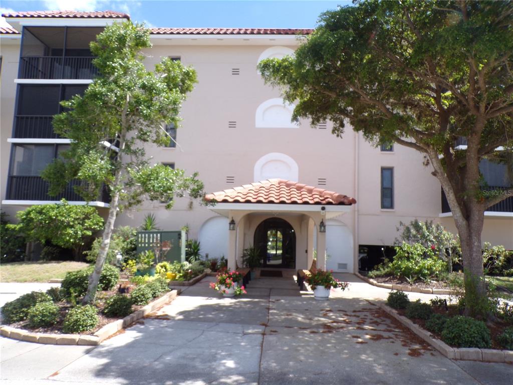 The exterior of a multi-story apartment building features a covered entrance with a tiled roof — 25188 MARION AVE UNIT A-309, PUNTA GORDA, FL