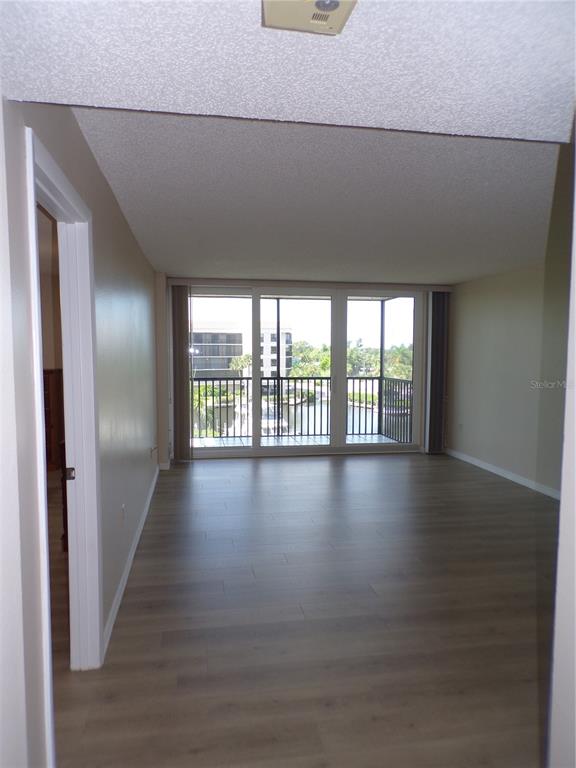 An empty living room with light wood-look flooring and a balcony overlooking a waterway — 25188 MARION AVE UNIT A-309, PUNTA GORDA, FL
