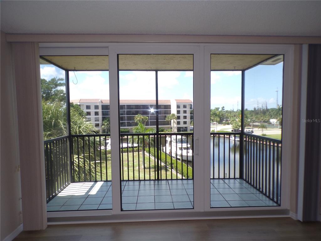 A view of a balcony with a tiled floor and black railings overlooking a canal — 25188 MARION AVE UNIT A-309, PUNTA GORDA, FL
