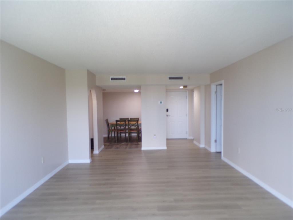 An open living area with light wood-look flooring leads to a dining space with chairs — 25188 MARION AVE UNIT A-309, PUNTA GORDA, FL