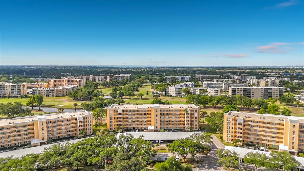 An aerial view shows several multi-story apartment buildings surrounded by trees and a golf course — 3740 PINEBROOK CIRCLE UNIT 607, BRADENTON, FL