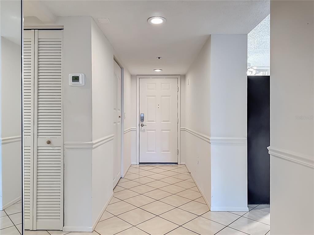 A white hallway features tiled floors, a front door, and a louvered closet door — 3740 PINEBROOK CIRCLE UNIT 607, BRADENTON, FL