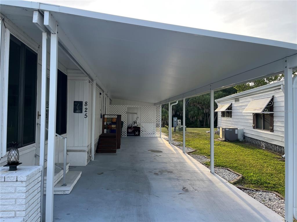A white mobile home features a long concrete carport and a small set of stairs — 825 JOLANDA CIRCLE, VENICE, FL