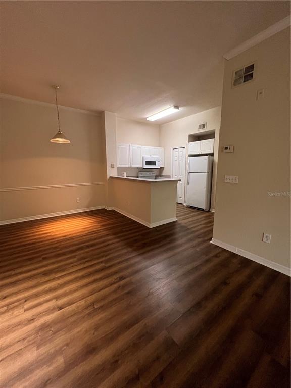 An open-concept kitchen with white cabinets and appliances overlooks a dining area with wood flooring — 18107 PEREGRINES PERCH PLACE UNIT 6310, LUTZ, FL
