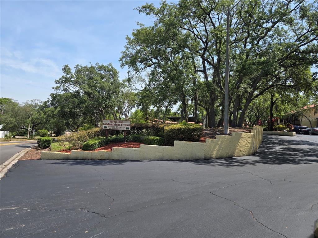 A sign for Forest Lake Condominium and Villas sits behind a tiered retaining wall — 7741 FOREST TRAIL UNIT 3, PORT RICHEY, FL