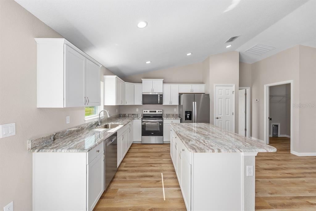 A kitchen with white cabinets, stainless steel appliances, and a large marble-patterned island countertop — 14362 SW 30TH PLACE, OCALA, FL
