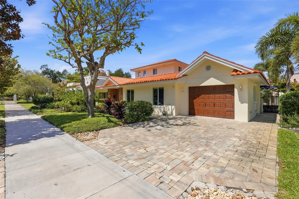 A single-story house with a terracotta tile roof, beige stucco walls, and a paved driveway — 125 23RD AVENUE NE, ST PETERSBURG, FL