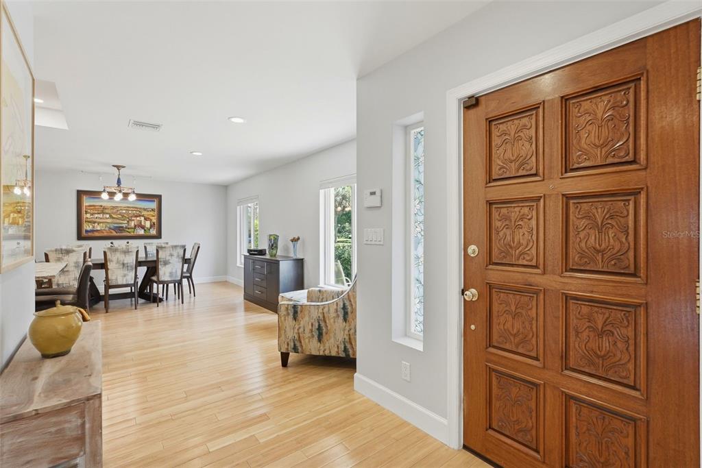 An entryway with a carved wooden door leads into a dining area with hardwood floors — 125 23RD AVENUE NE, ST PETERSBURG, FL