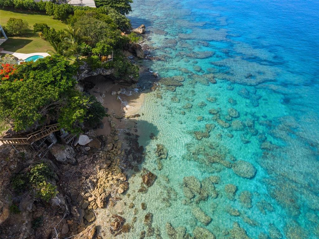 A sandy beach with wooden stairs leading up a rocky cliffside to lush greenery — Lot 4 IBIZA ST, RD 107 KM 2.7, AGUADILLA, PR