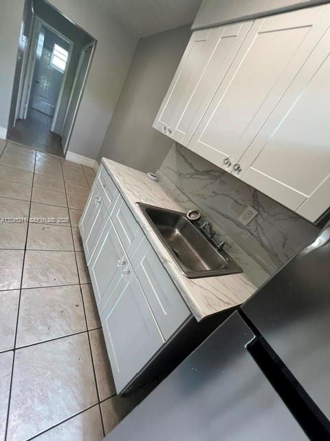 A kitchen features white cabinets, a stainless steel sink, and marble-patterned countertops — FORT LAUDERDALE, FL