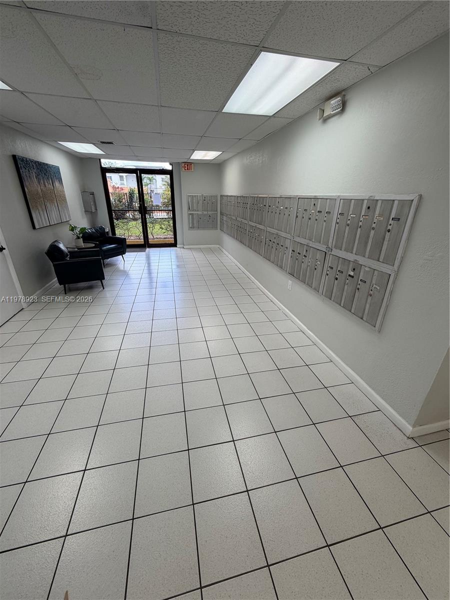A lobby features white tiled floors, a wall of metal mailboxes, and two black chairs — 1800 W 54th St # 309, Hialeah FL 33012, HIALEAH, FL