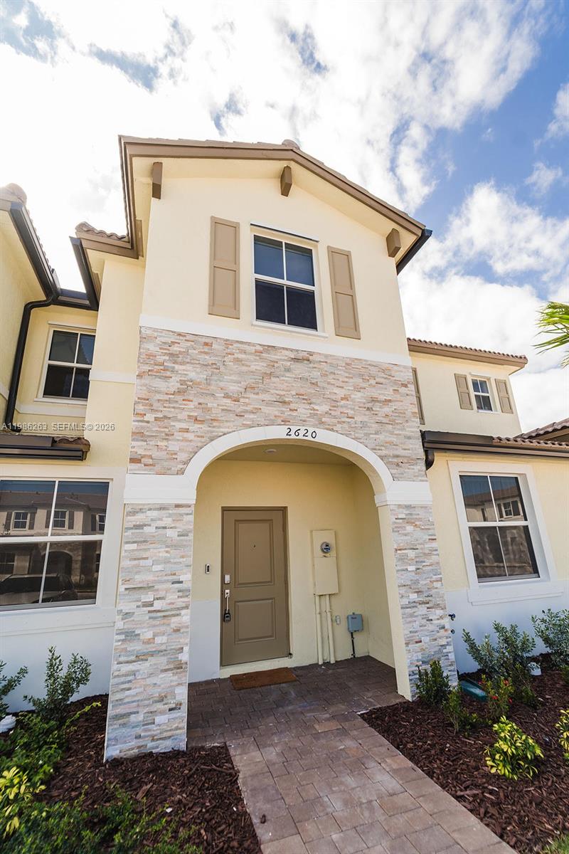 The exterior of a two-story house features a stone-accented entryway and a brown front door — 2620 SE 28th Dr, Homestead FL 33035, HOMESTEAD, FL