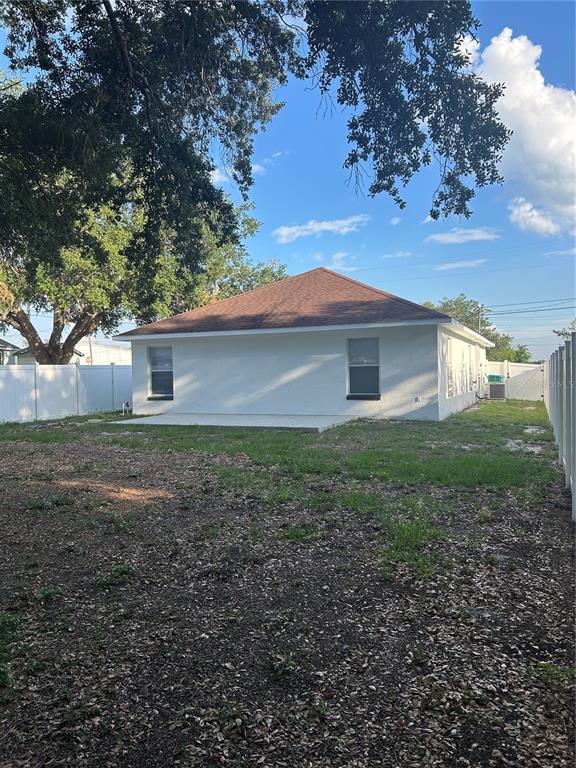 The exterior rear view of a white house features a brown roof and two windows — 702 LEMON AVE, DUNDEE, FL