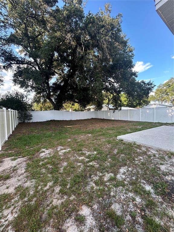 A fenced backyard features a large oak tree and a concrete patio — 702 LEMON AVE, DUNDEE, FL