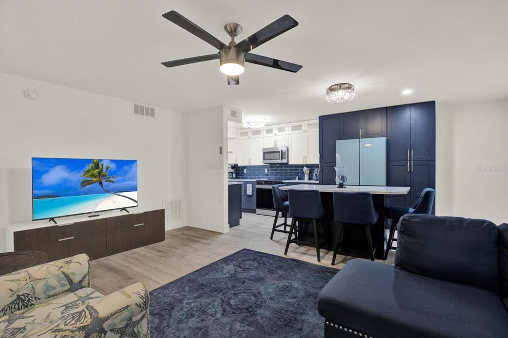 An open-concept living room and kitchen featuring dark blue cabinetry and a central island — 8911 BLIND PASS ROAD UNIT 120, ST PETE BEACH, FL
