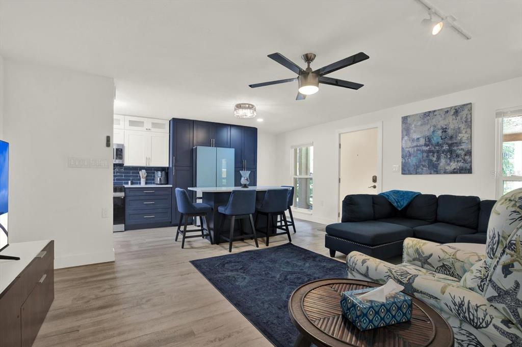 An open-concept living room and kitchen featuring dark blue cabinetry, a central island, and furniture — 8911 BLIND PASS ROAD UNIT 120, ST PETE BEACH, FL