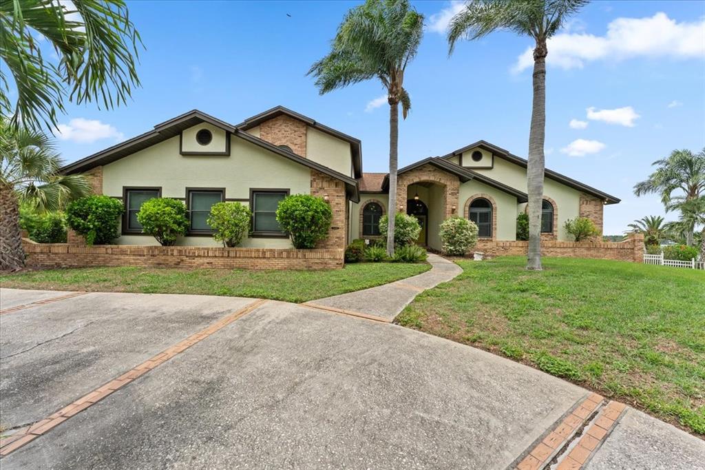 A single-story house with a brick and stucco exterior, arched windows, and a concrete driveway — 1589 MARY LANE, TARPON SPRINGS, FL