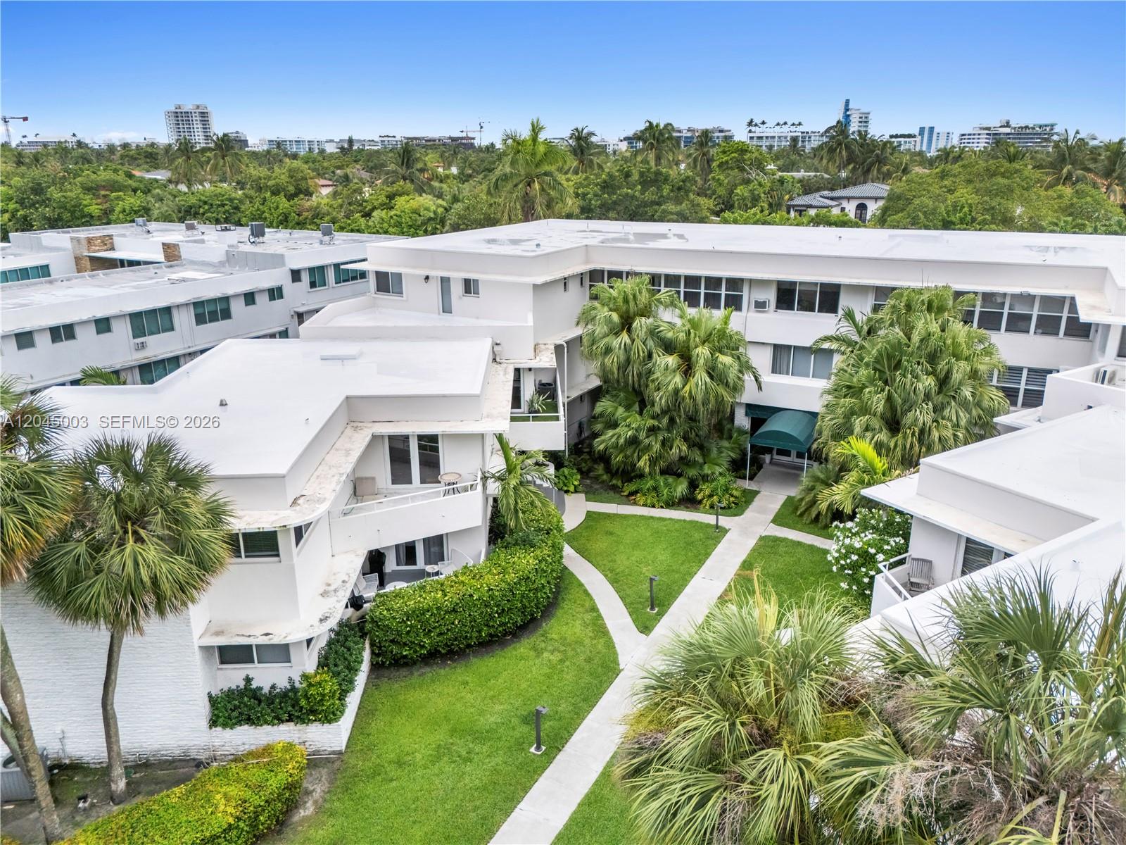 An aerial view shows white multi-story apartment buildings surrounding a landscaped courtyard with walkways — 10190 Collins Ave # 203, Bal Harbour FL 33154, BAL HARBOUR, FL