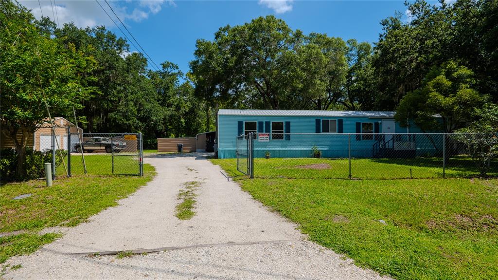 A light blue mobile home sits behind a chain-link fence with a gravel driveway — 312 DONALD LANE, WINTER HAVEN, FL