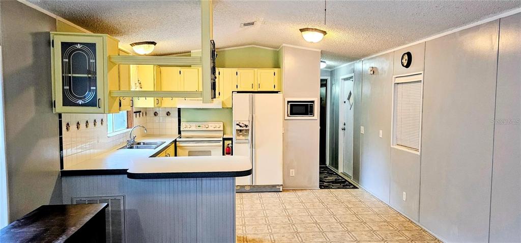 A kitchen features yellow cabinets, white appliances, a breakfast bar, and a patterned tile floor — 312 DONALD LANE, WINTER HAVEN, FL