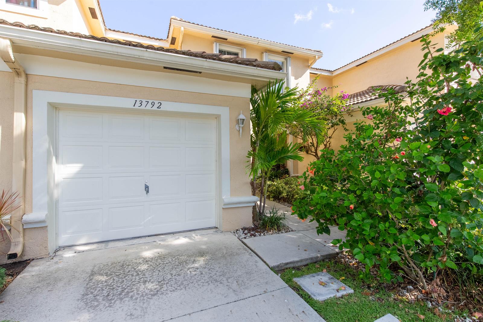 A beige two-story house features a white garage door and a landscaped front walkway — 13792 Creston Place, Wellington FL 33414, WELLINGTON, FL