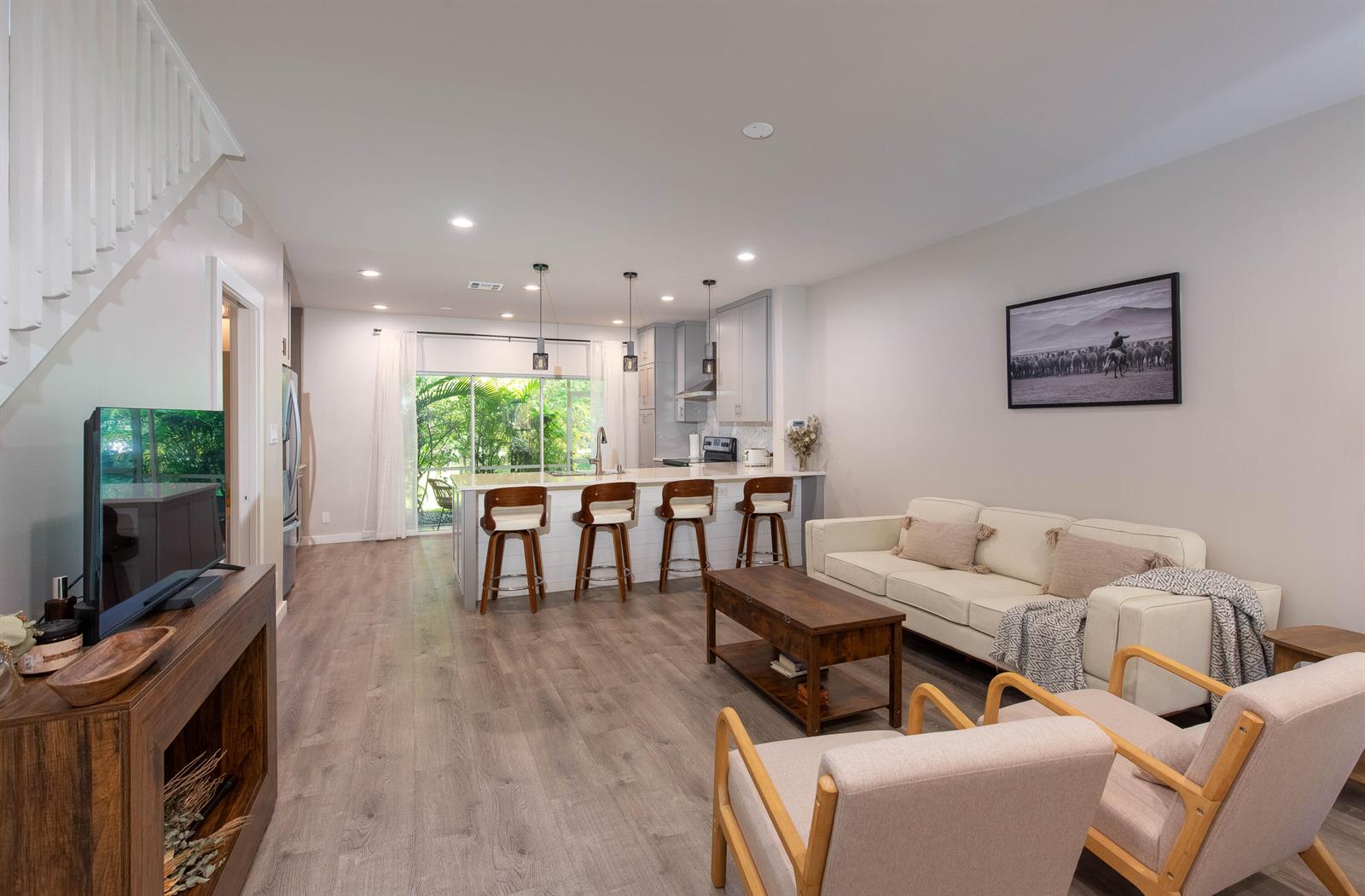 An open-concept living room and kitchen featuring wood-look flooring, a breakfast bar, and sliding doors — 13792 Creston Place, Wellington FL 33414, WELLINGTON, FL