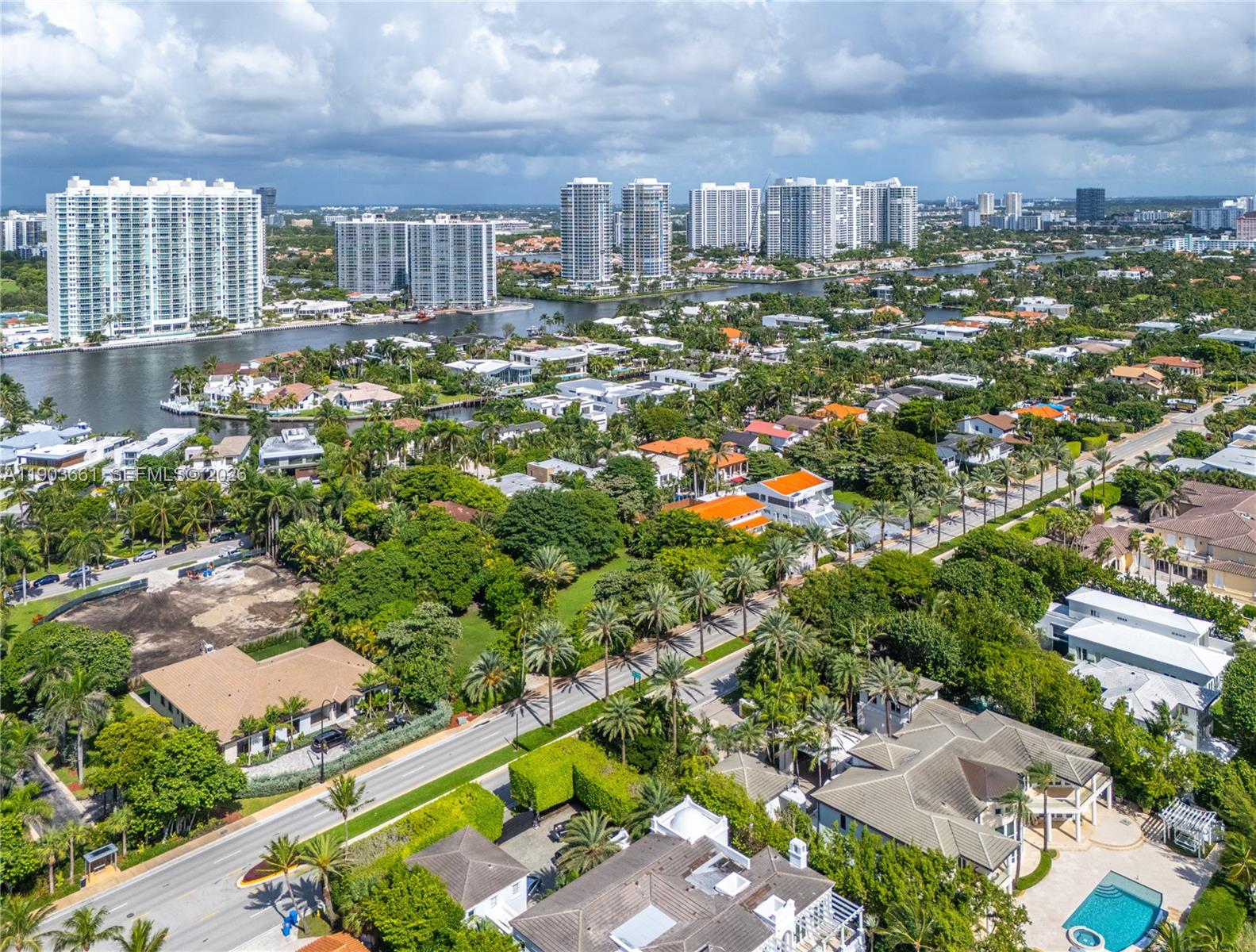 An aerial view shows a residential neighborhood with palm trees, houses, and distant high-rise buildings — 326 Ocean Blvd, Golden Beach FL 33160, GOLDEN BEACH, FL